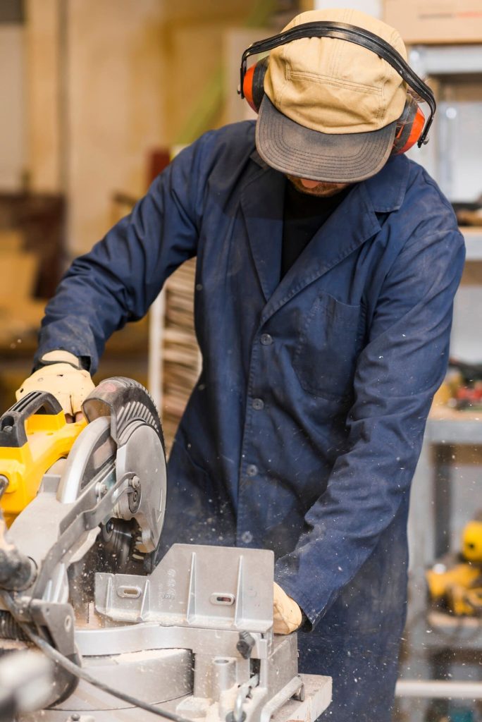 Male carpenter using some power tools for his work in a woodshop